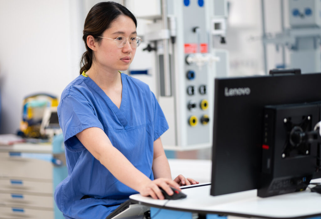 A woman in blue uniform sat in front of a computer