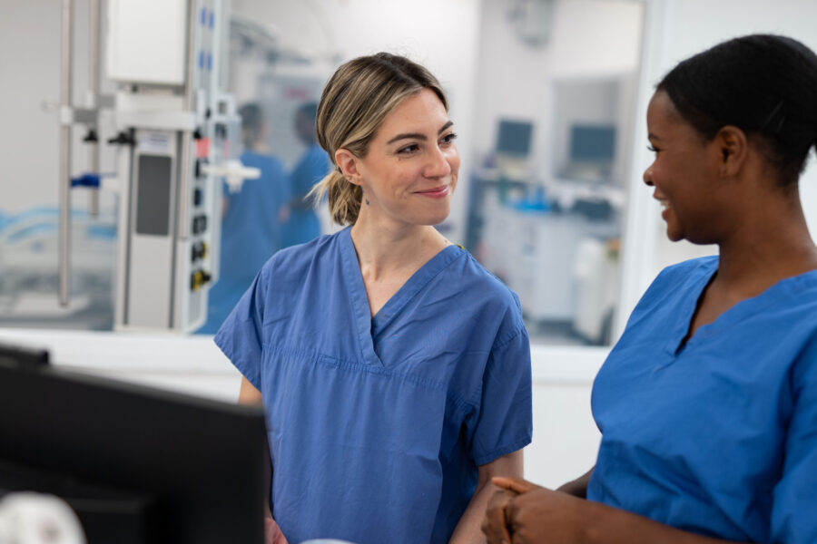 Two healthcare colleagues in blue having a conversation